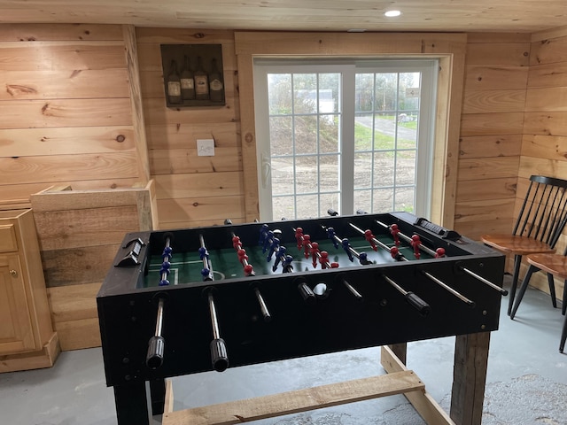 recreation room featuring wood walls and concrete flooring