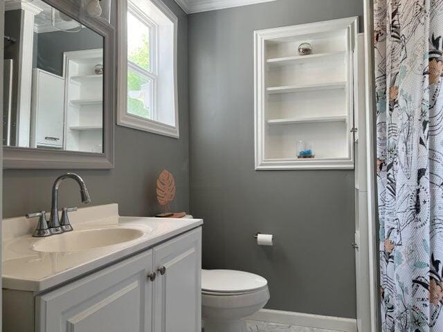 bathroom featuring toilet, crown molding, and vanity