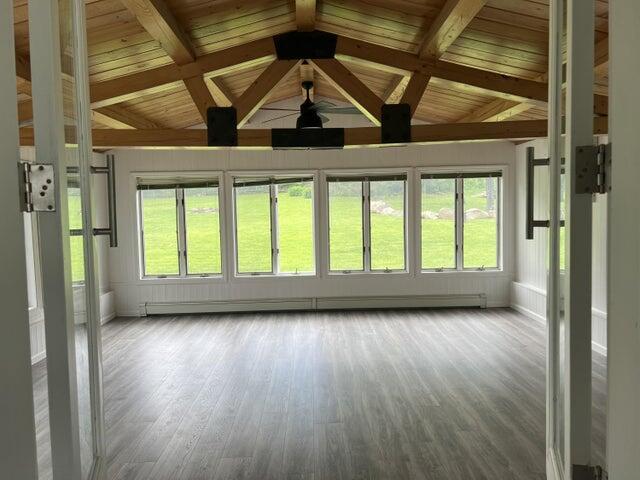 unfurnished sunroom featuring a baseboard heating unit, wooden ceiling, and lofted ceiling with beams