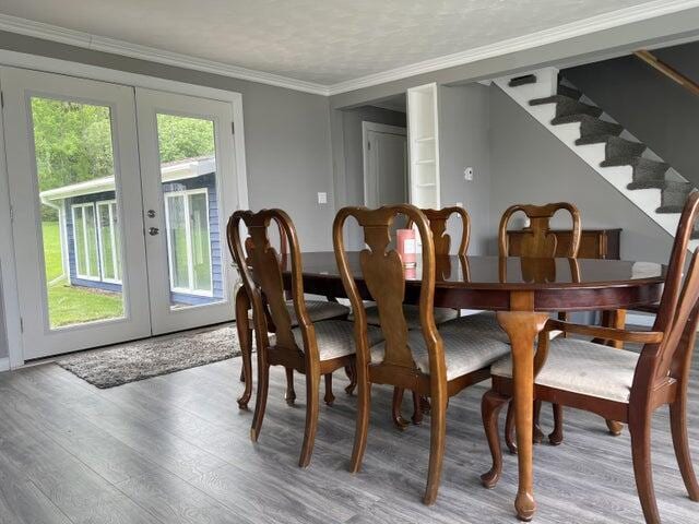 dining space featuring hardwood / wood-style floors, plenty of natural light, crown molding, and french doors