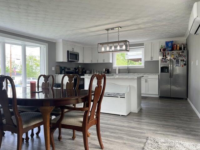 dining space featuring a wall mounted AC, light hardwood / wood-style flooring, and sink