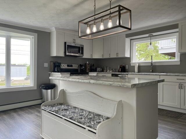 kitchen with decorative light fixtures, stainless steel appliances, a kitchen breakfast bar, sink, and light stone counters