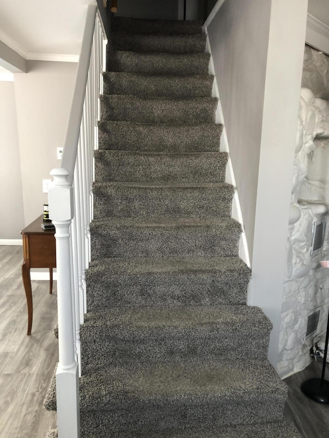 staircase featuring crown molding and hardwood / wood-style flooring