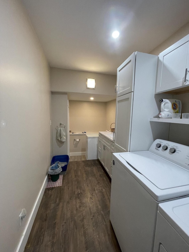 laundry area featuring cabinets, washer and clothes dryer, and dark hardwood / wood-style flooring