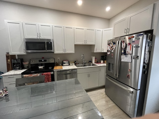 kitchen featuring sink, white cabinets, light wood-type flooring, and appliances with stainless steel finishes
