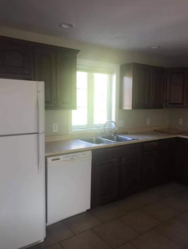kitchen featuring sink, white appliances, dark tile patterned floors, and dark brown cabinets