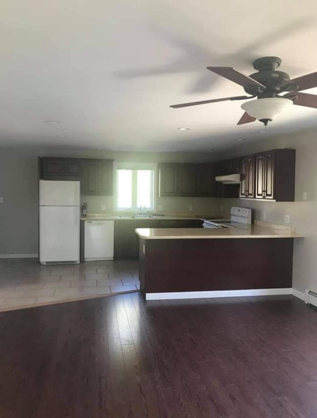 kitchen with kitchen peninsula, ceiling fan, dark wood-type flooring, white appliances, and dark brown cabinetry