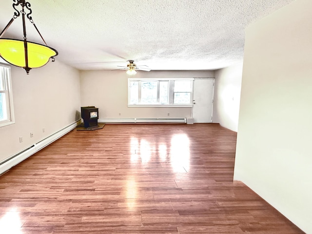 unfurnished room with ceiling fan, a baseboard radiator, a textured ceiling, and wood-type flooring