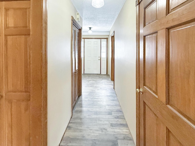 hallway featuring light wood-type flooring and a textured ceiling