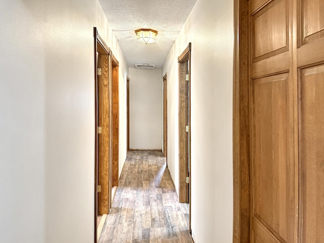 corridor featuring a textured ceiling and hardwood / wood-style floors