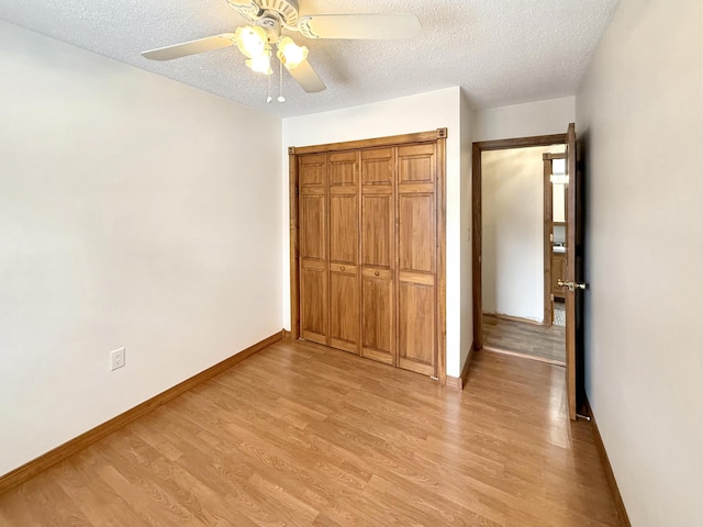 unfurnished bedroom featuring a closet, ceiling fan, light hardwood / wood-style flooring, and a textured ceiling