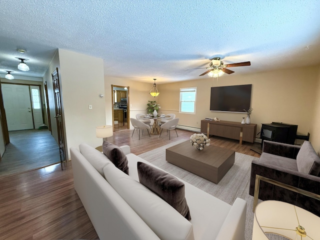 living room with hardwood / wood-style flooring, baseboard heating, and a textured ceiling