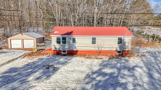 snow covered property with a garage and an outbuilding