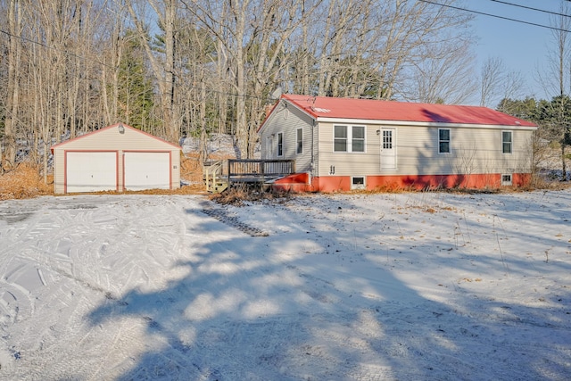 view of snowy exterior featuring a deck, an outdoor structure, and a garage