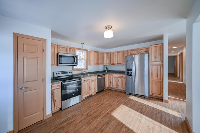 kitchen featuring appliances with stainless steel finishes, decorative light fixtures, light brown cabinets, light hardwood / wood-style floors, and sink