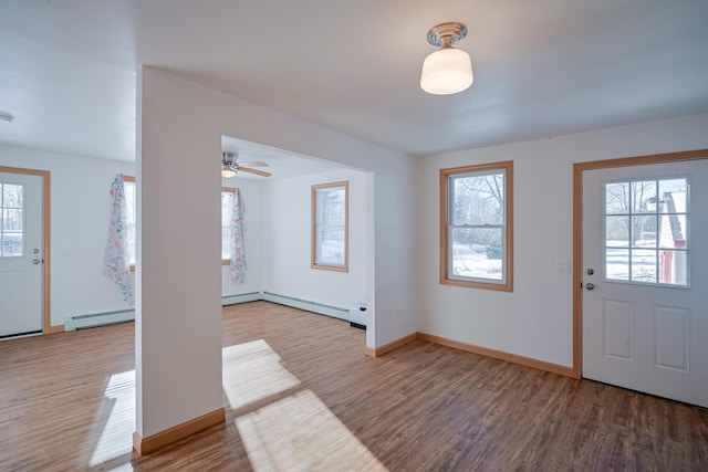 foyer with baseboard heating, wood-type flooring, and ceiling fan