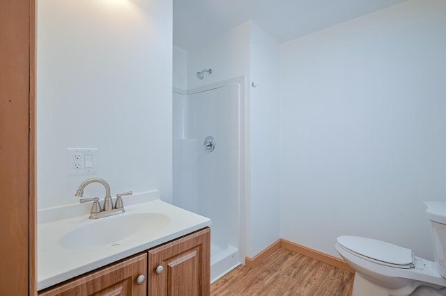 bathroom featuring toilet, a shower, hardwood / wood-style floors, and vanity