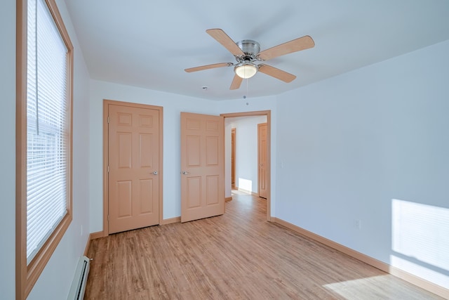 unfurnished bedroom featuring ceiling fan, light hardwood / wood-style floors, multiple windows, and baseboard heating