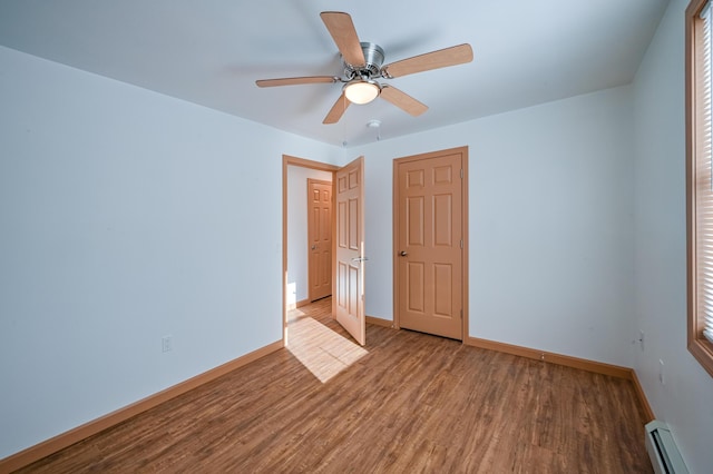 interior space featuring baseboard heating, wood-type flooring, and ceiling fan