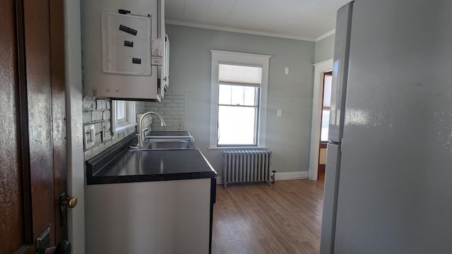 kitchen with sink, white refrigerator, tasteful backsplash, radiator, and water heater