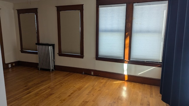 unfurnished room featuring radiator and light hardwood / wood-style flooring