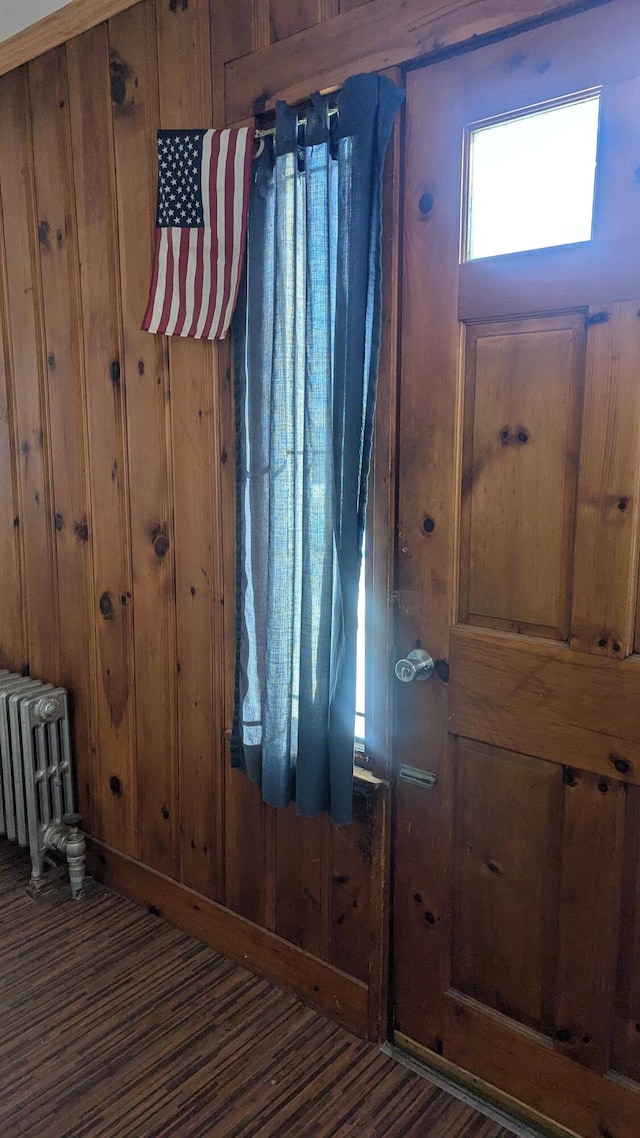 foyer with dark hardwood / wood-style flooring, radiator, and wood walls