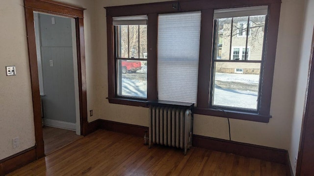 empty room with hardwood / wood-style flooring and radiator