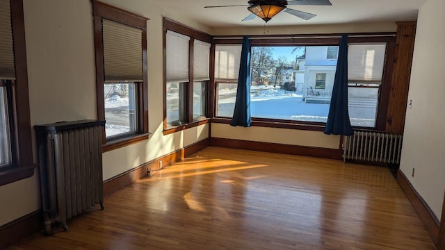 spare room with hardwood / wood-style flooring, radiator, and ceiling fan