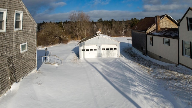 view of snow covered exterior with a garage and an outdoor structure