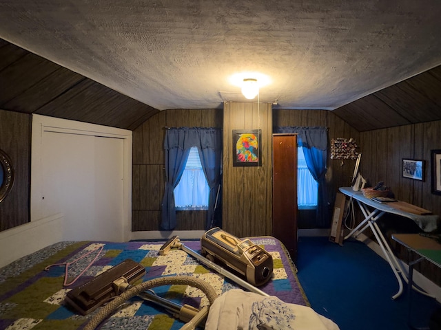 carpeted bedroom featuring lofted ceiling, a closet, wooden walls, and a textured ceiling