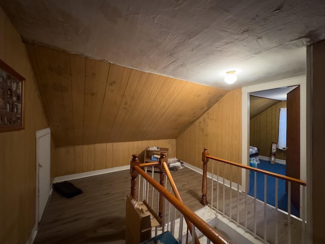 bonus room with vaulted ceiling, wood walls, and dark hardwood / wood-style floors