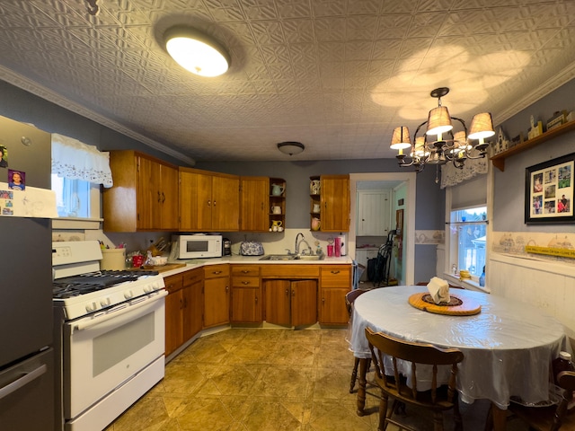 kitchen featuring crown molding, sink, pendant lighting, and white appliances