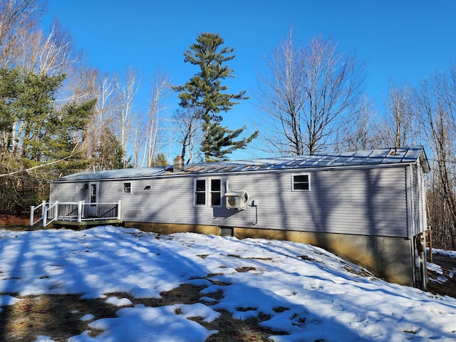 snow covered back of property featuring a wooden deck