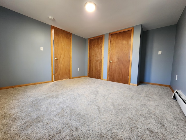 unfurnished bedroom with multiple closets, a baseboard heating unit, and carpet flooring