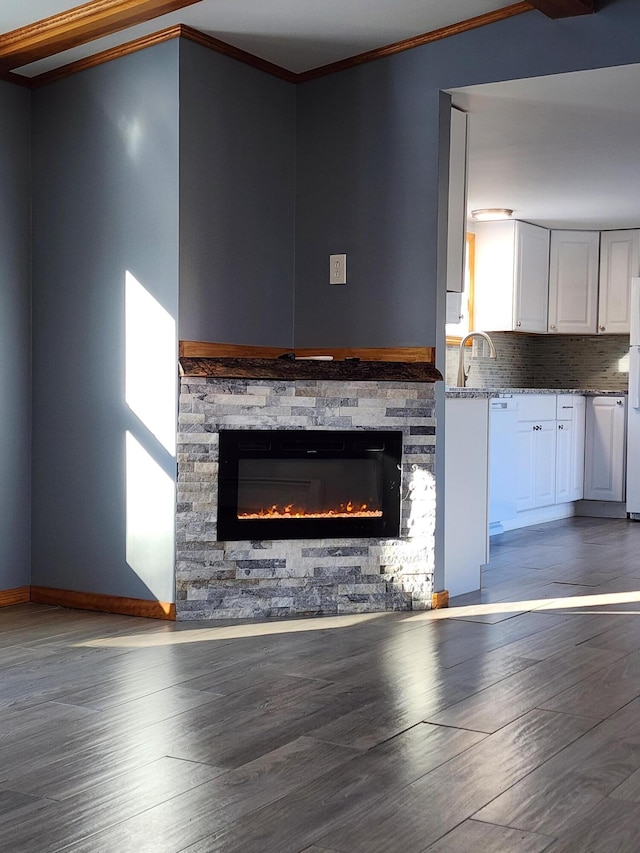 unfurnished living room featuring ornamental molding, wood-type flooring, and a stone fireplace