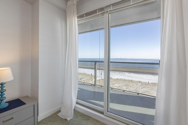 interior space with light colored carpet, a beach view, and a water view