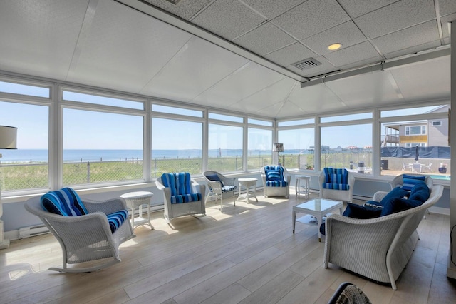 sunroom with a baseboard heating unit and a water view