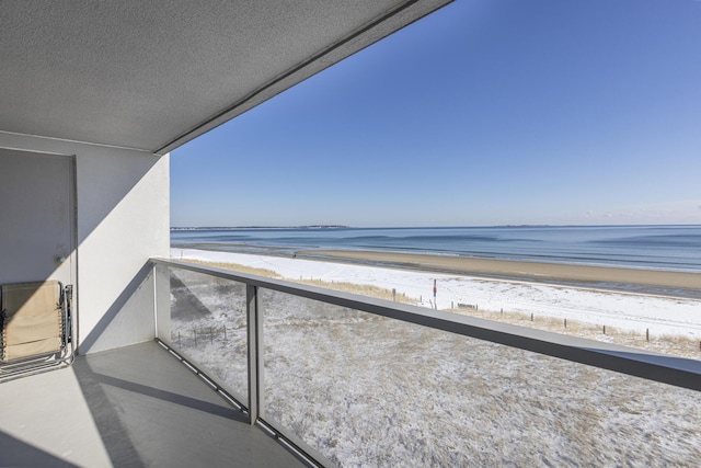 balcony featuring a view of the beach and a water view