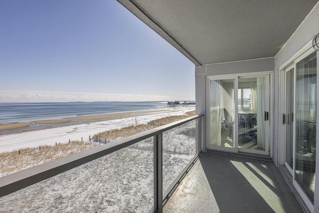 balcony featuring a water view and a beach view