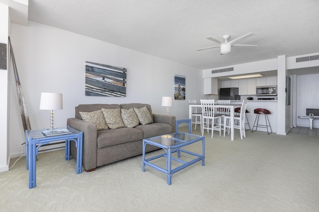 carpeted living room featuring ceiling fan and a textured ceiling