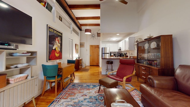 living room with beam ceiling, light hardwood / wood-style flooring, and a towering ceiling