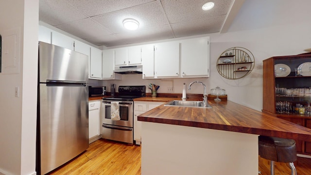 kitchen featuring sink, butcher block counters, white cabinetry, stainless steel appliances, and kitchen peninsula