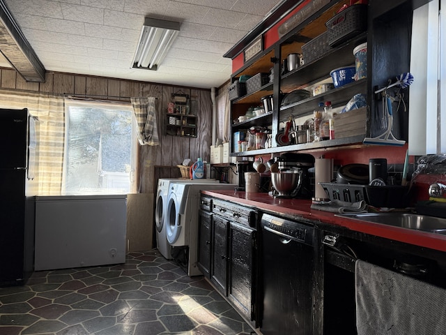 clothes washing area with sink, independent washer and dryer, and wooden walls