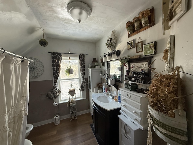 bathroom with hardwood / wood-style flooring, toilet, vanity, and lofted ceiling