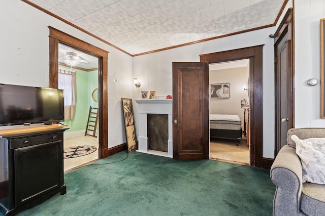 living room with ceiling fan, ornamental molding, and dark colored carpet