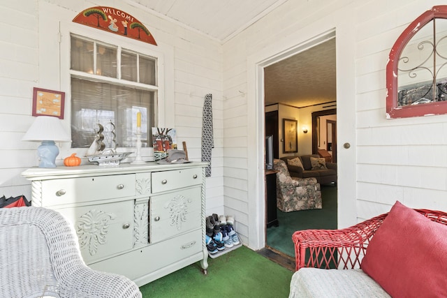 sitting room featuring wooden walls and dark carpet