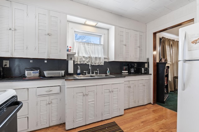 kitchen featuring sink, white refrigerator, tasteful backsplash, white cabinets, and light wood-type flooring