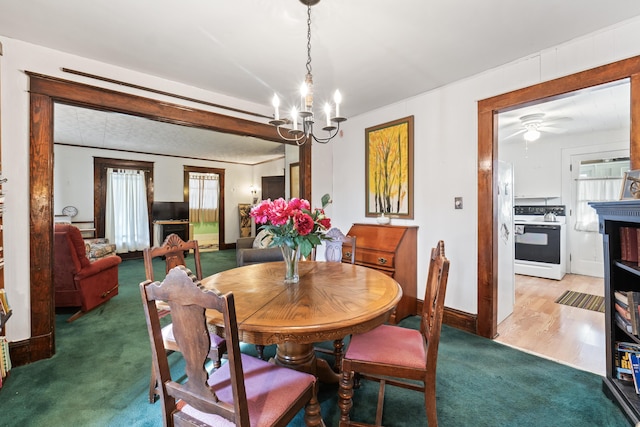 carpeted dining area with ceiling fan with notable chandelier