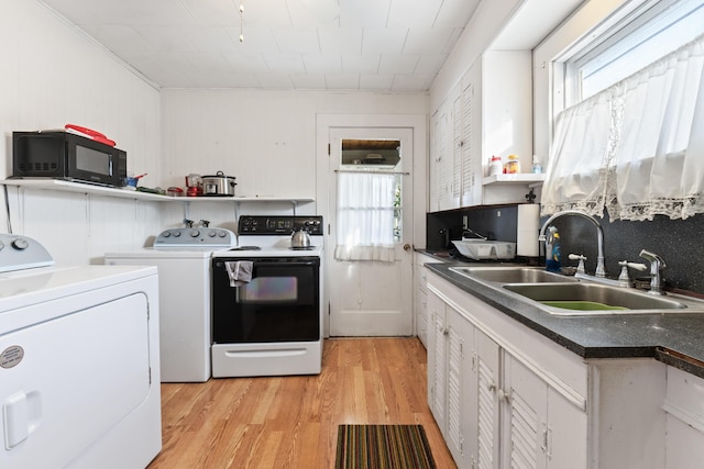 kitchen featuring electric range oven, white cabinetry, sink, washing machine and dryer, and light hardwood / wood-style flooring