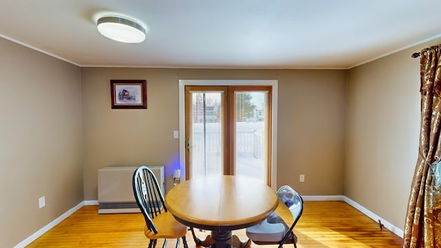 dining area with ornamental molding and light hardwood / wood-style floors